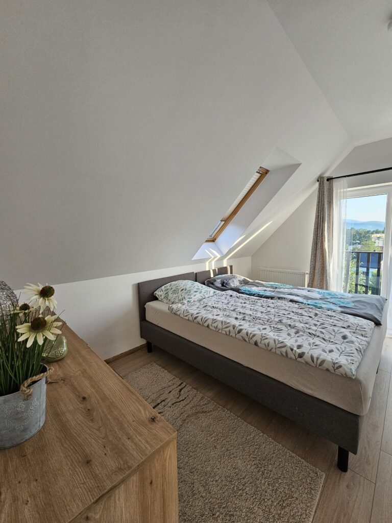 Sypialnia z dwoma podwójnymi łóżkami, szafami i balkonem w domu wakacyjnym w Lądku-Zdroju