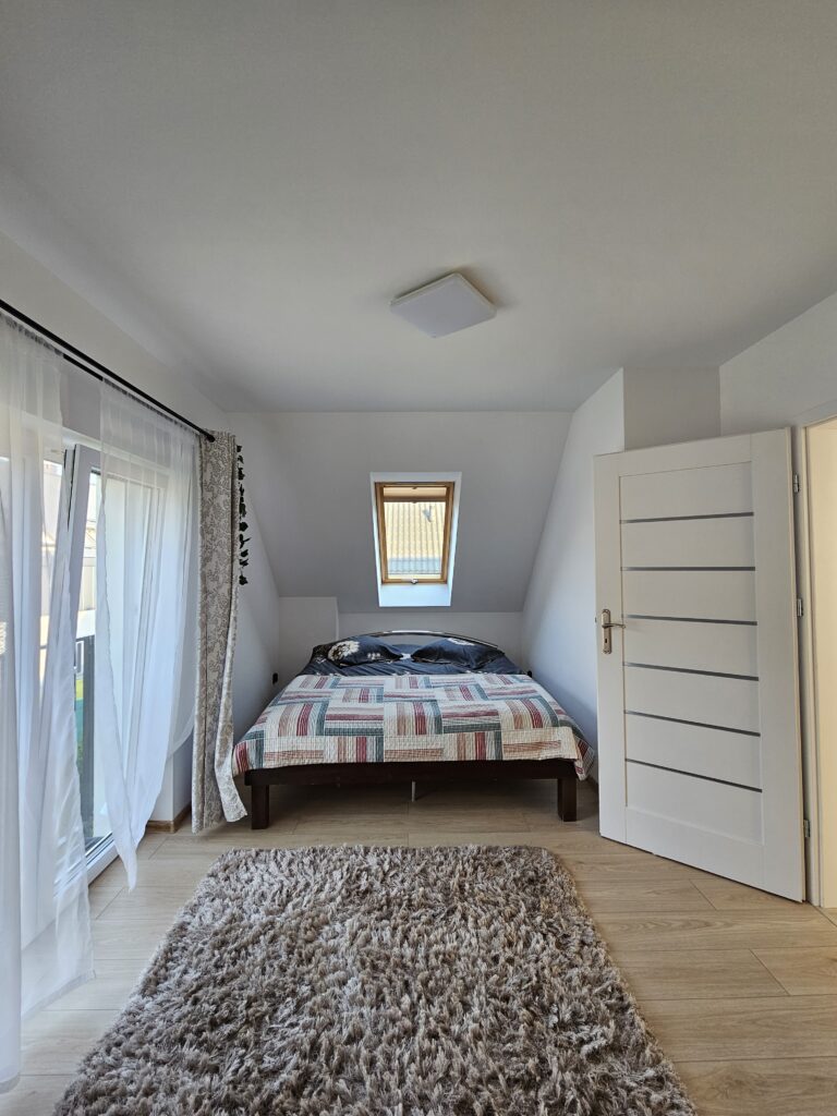 Sypialnia z podwójnym łóżkiem, szafami i balkonem w domu wakacyjnym w Lądku-Zdroju